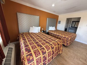 A hotel room with two beds, a heater, and a kitchenette.