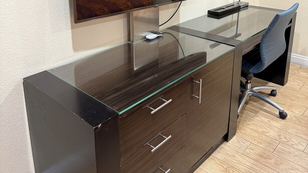 Un bureau moderne, doté d’un écran plat, d’une télécommande et d’un tableau encadré accroché au mur.