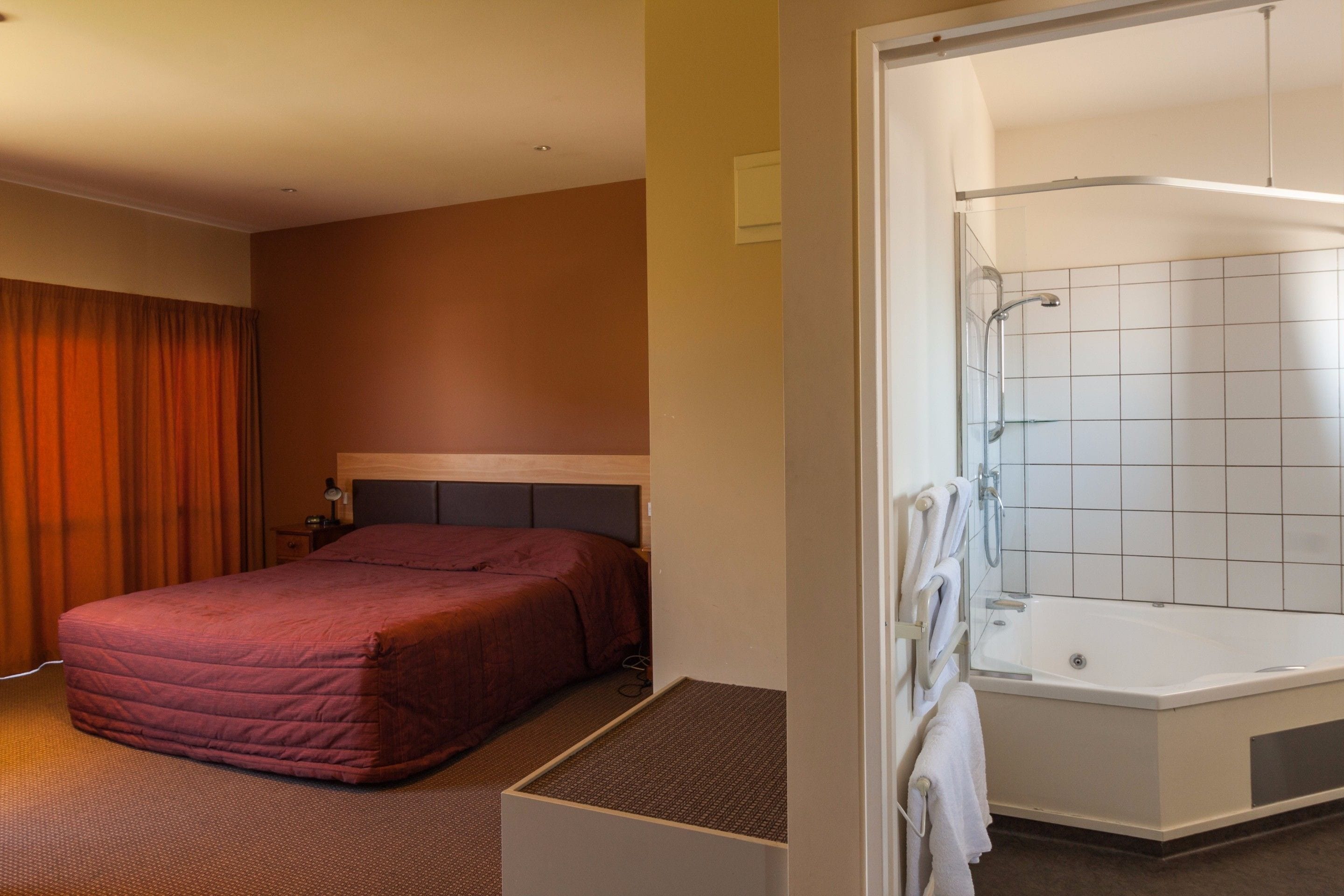 Une chambre d’hôtel avec un lit, une douche et une petite table de chevet.