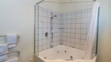 A corner shower with a glass enclosure, a white bathtub, and a towel rack with towels.