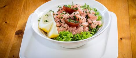 A white bowl of shrimp salad on a wooden table.