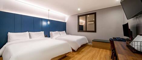 Une chambre d’hôtel avec deux lits, un bureau avec une chaise, un téléviseur à écran plat et un grand miroir au mur.