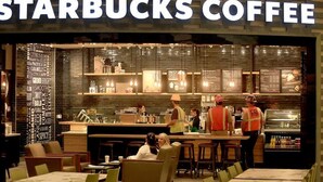 Un Starbucks Coffee con una decoración moderna, baristas uniformados y clientes sentados en mesas.
