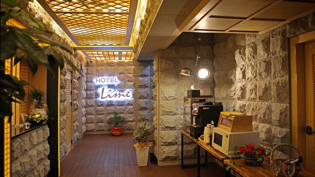 A hotel lobby with a stone wall, a neon sign reading "HOTEL Lima", a reception desk, and a wooden floor. - Jeonju Lime Hotel (Jeonju)