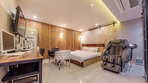 A modern hotel room with a wooden panel wall, a bed, a massage chair, a desk with a computer, and a chair. - Jeonju Lime Hotel (Jeonju)