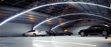 A parking garage with three cars parked under a curved ceiling with illuminated lines.