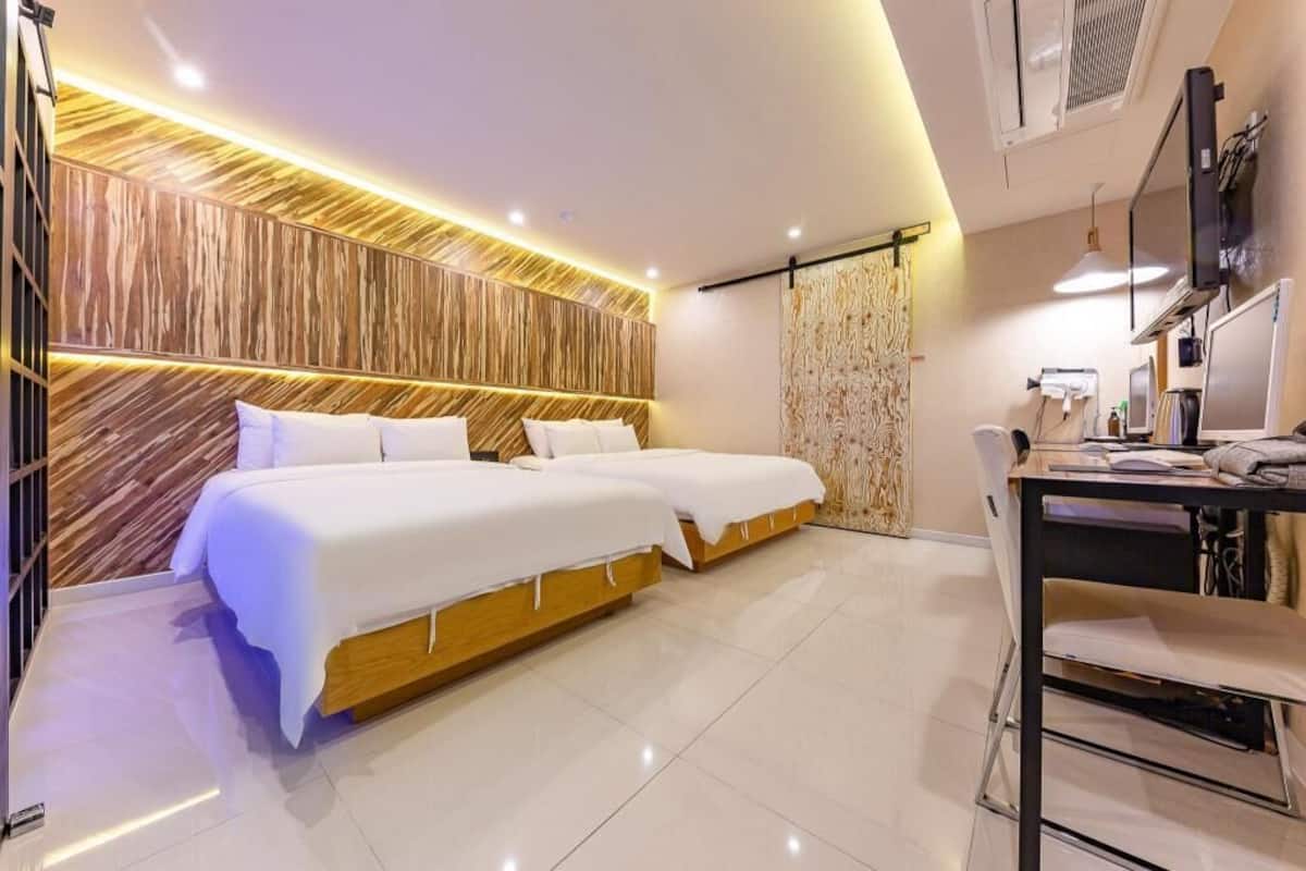 A modern hotel room with a large bed, a desk, and a TV.