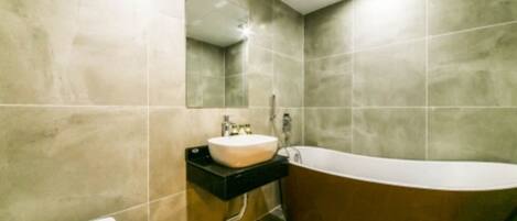 A modern bathroom with a freestanding bathtub, a sink with a mirror above it, and a toilet.