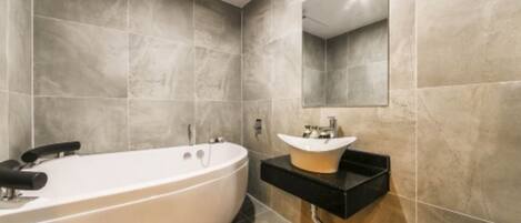 Un baño moderno con una bañera independiente, un tocador con lavamanos y un espejo en la pared.