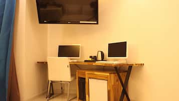Un espacio de oficina pequeño con dos escritorios, un televisor y un refrigerador.