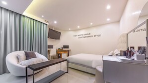 A modern hotel room with a sofa, a bed, a desk, and a TV. - Jeonju Lime Hotel (Jeonju)