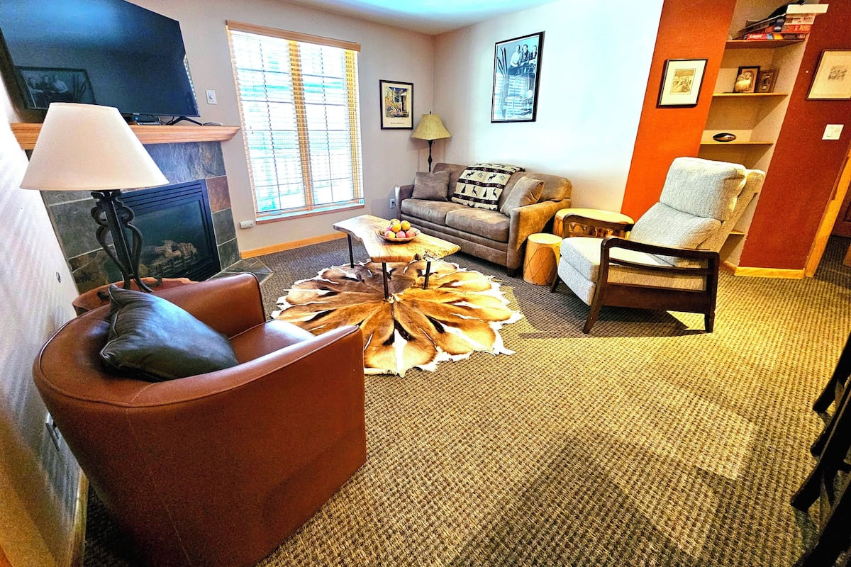 A living room with a sofa, armchair, coffee table, and a fireplace.