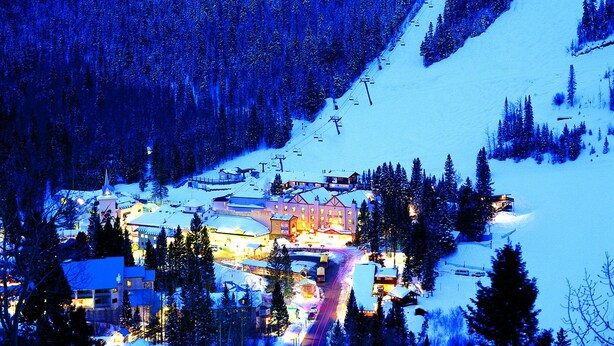 A snow-covered mountain town with a ski lift, buildings, and a road. - Snakedance Condominiums (Taos Ski Valley)