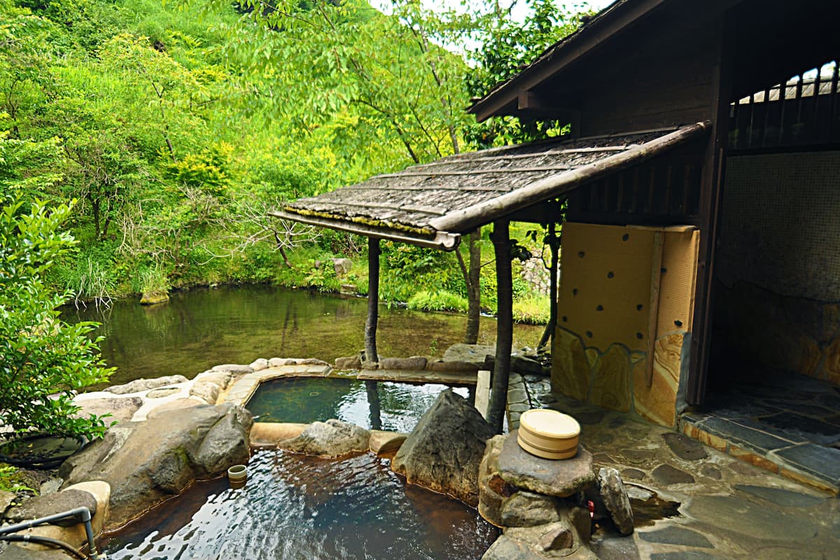 Um onsen japonês tradicional com estrutura de madeira e bacia de pedra.
