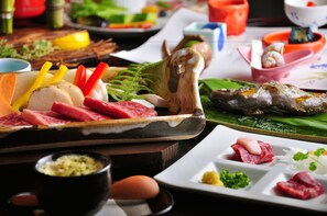 A variety of food items including sliced meats, vegetables, and fish on a wooden table.