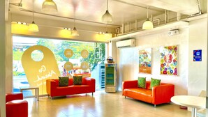 Een moderne lobby met twee rode banken, een automaat en een muur met een reisthema.