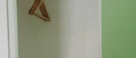 A room with a white door, a metal rod, and a wooden hanger.
