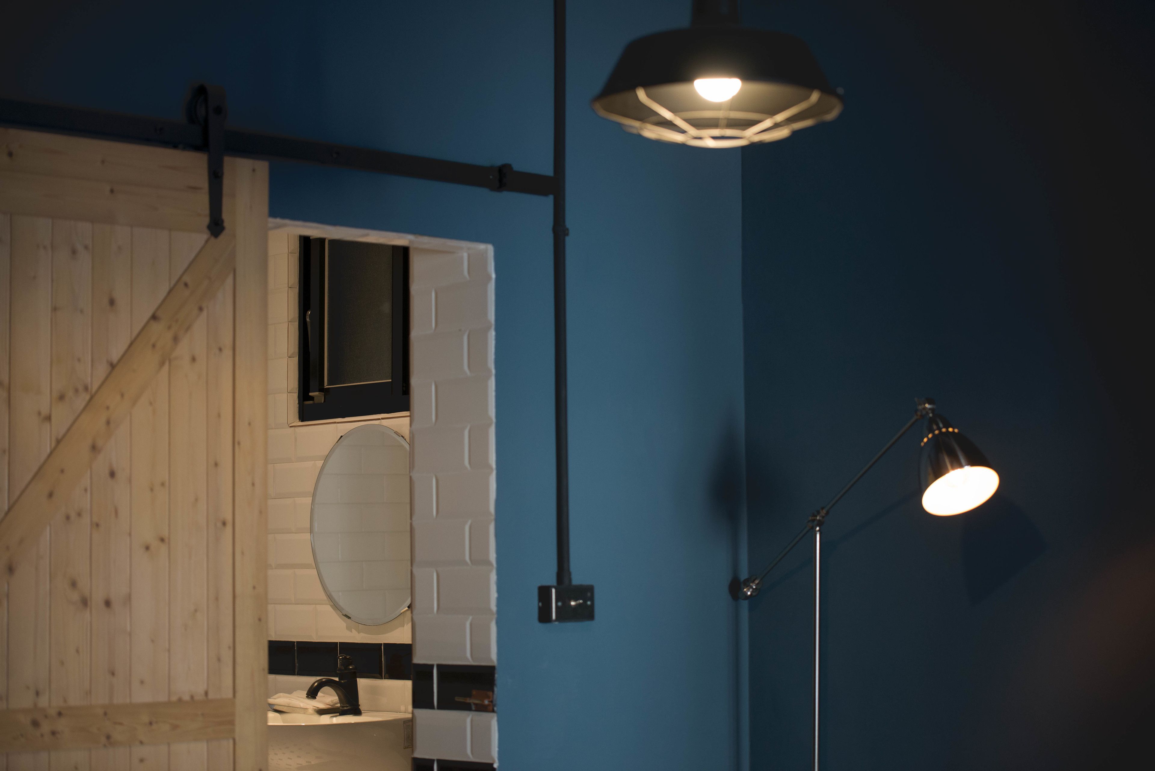 A bathroom with a wooden staircase, a white sink, a mirror, and a hanging light fixture.