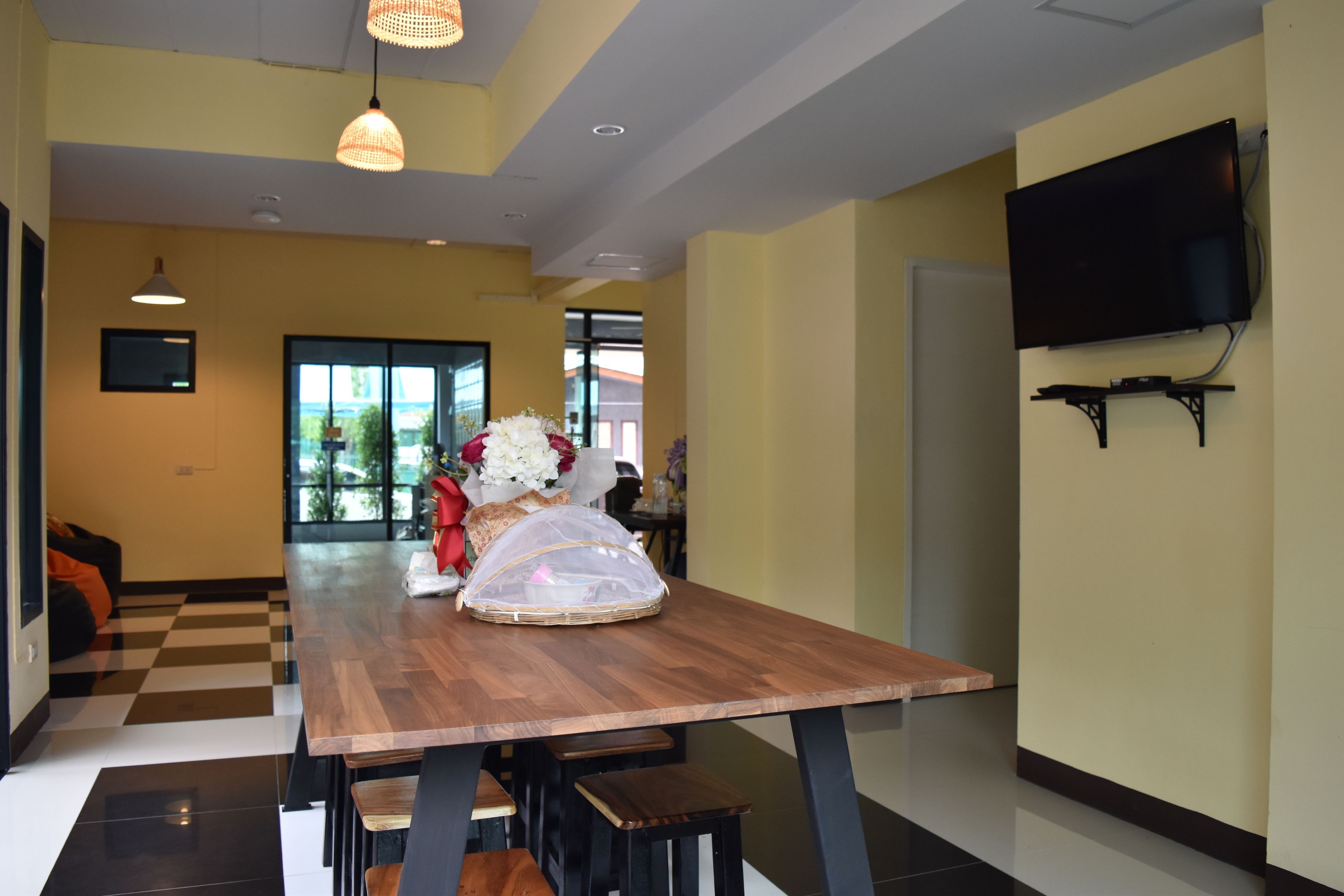A modern dining area with a wooden table, benches, and a vase of flowers.