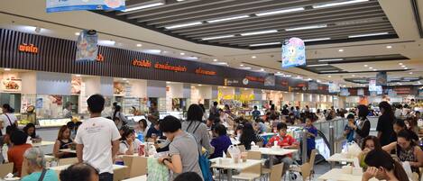 A busy food court with multiple dining areas and people eating.