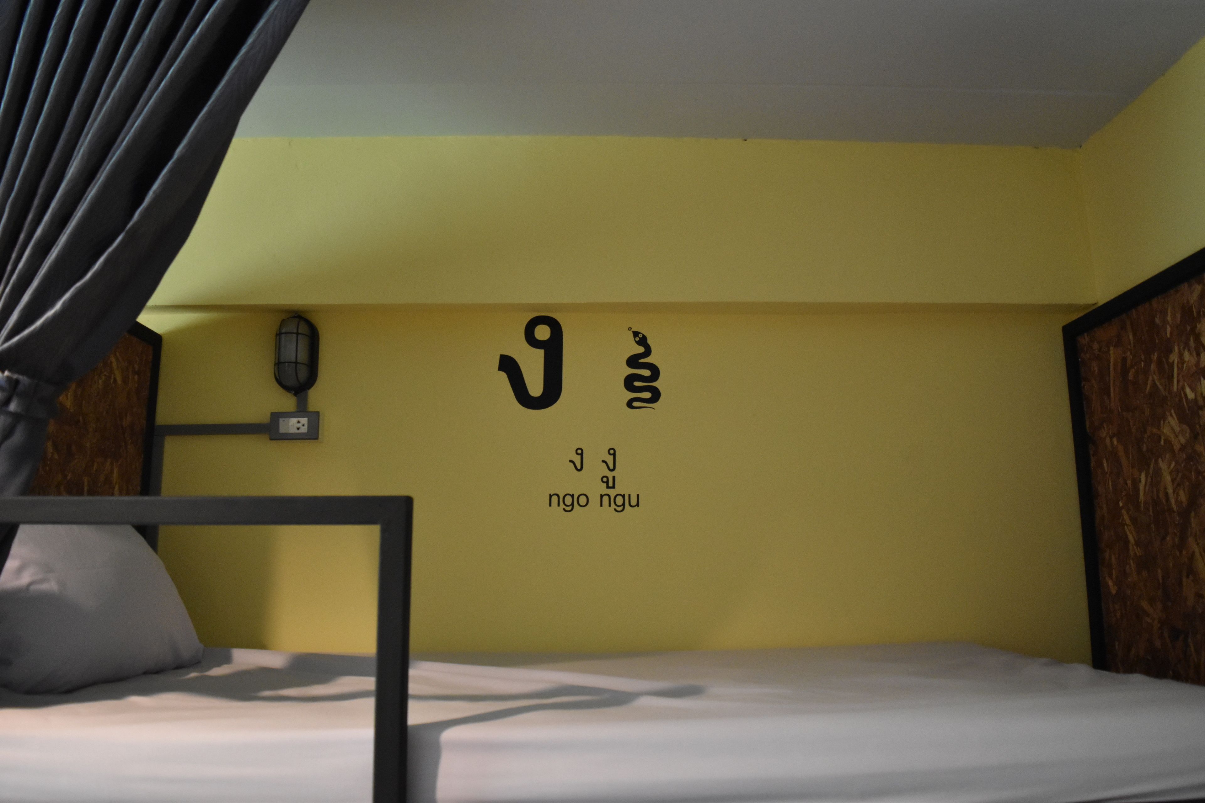 A room with a bed, a wall-mounted light, and a wall with text.