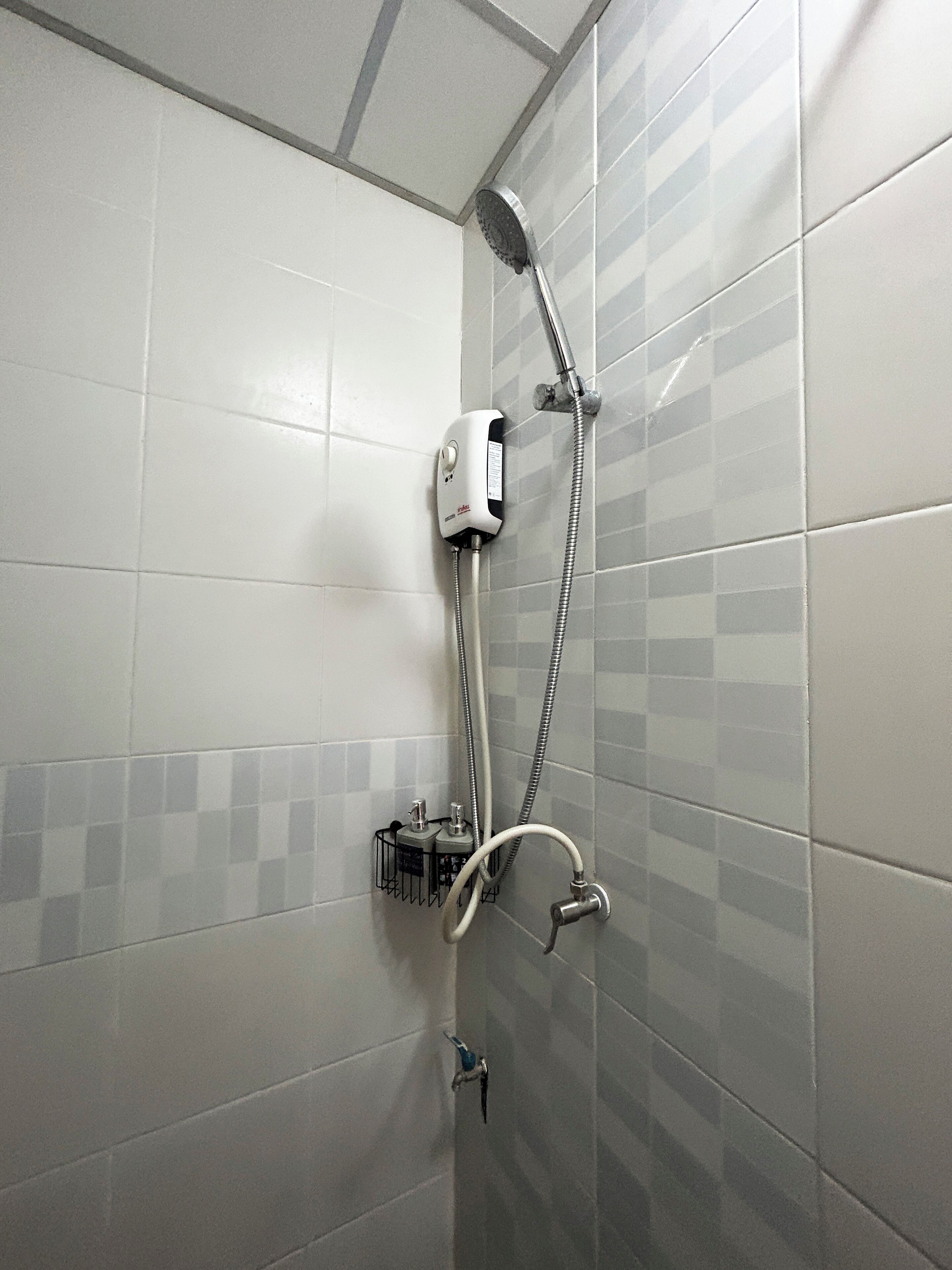 A shower with a handheld showerhead and a wall-mounted control panel.