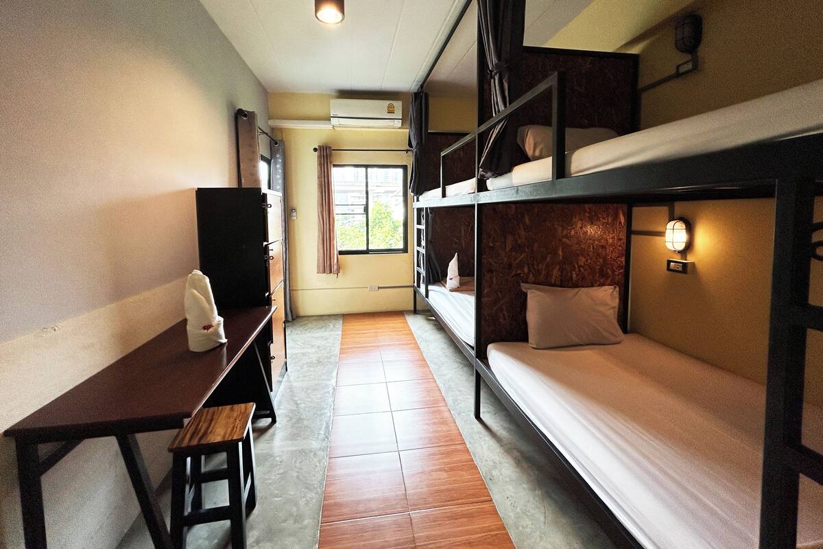 Une chambre de dortoir avec des lits superposés, un bureau et une chaise.