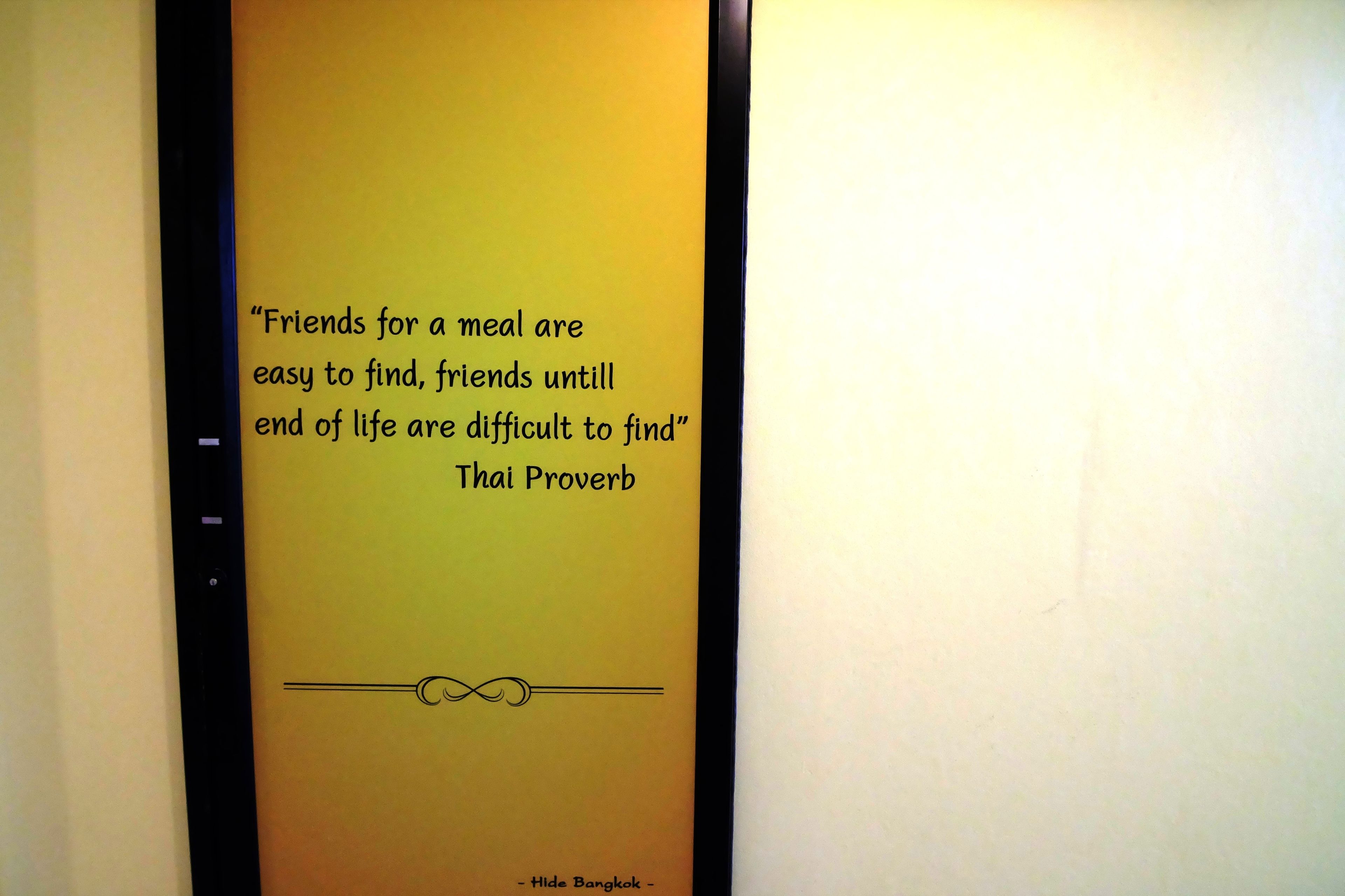 A wall with a quote from a Thai proverb.