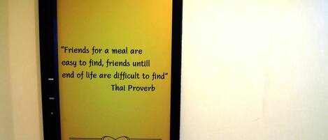 A wall with a quote from a Thai proverb.