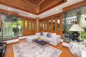 A modern living room with a white sofa, glass coffee table, and a decorative lamp. - Baan Bua Estate by Tropiclook (Rawai)