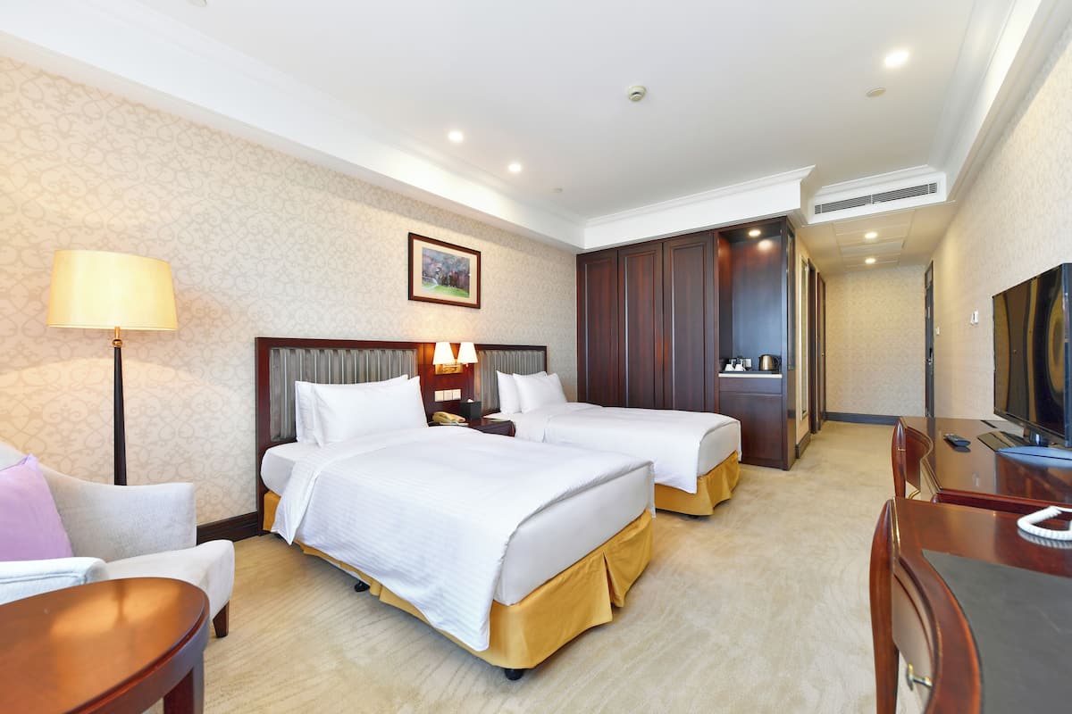 Een hotelkamer met twee bedden, een bureau, een televisie en een badkamer met douche en toilet.