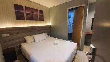 A hotel room with a large bed, a headboard, and three wall-mounted paintings.