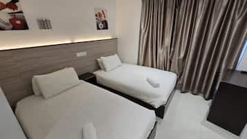 A hotel room with two beds, a wooden headboard, a small desk, and a large window with curtains.