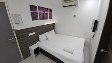 Un dormitorio ordenado con cama, mesita de noche pequeña, aire acondicionado de pared y toma de corriente.