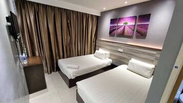 Habitación de hotel con dos camas individuales, televisión y un ventanal grande con cortinas.