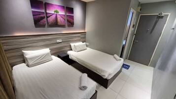 A hotel room with two beds, a wooden headboard, a wall-mounted artwork, and a door to the right.