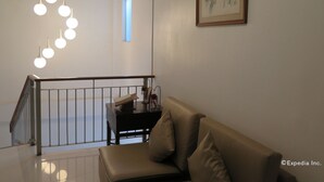 Un interior moderno con una escalera, un sofá de cuero y una obra enmarcada en la pared.