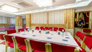 Une salle de conférence avec une longue table, des chaises rouges et un grand tableau accroché au mur.