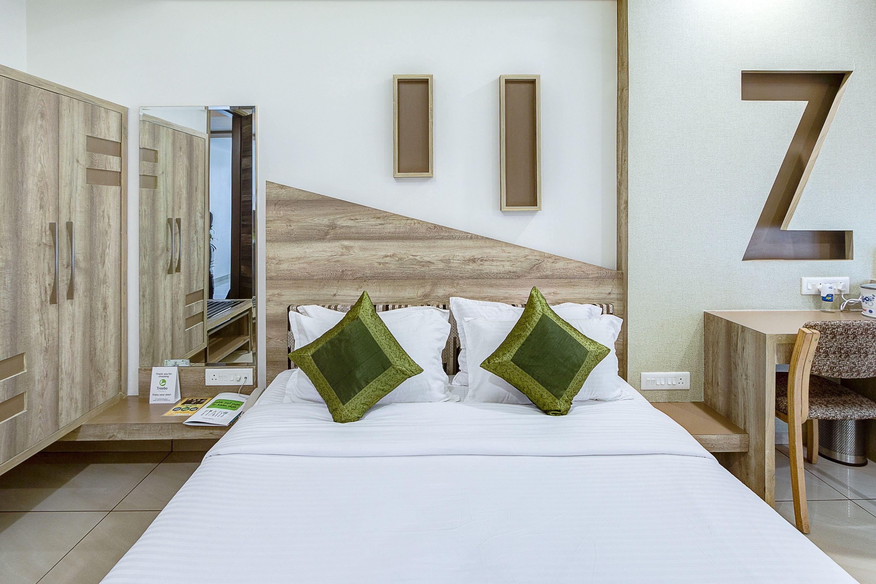 A hotel room with a bed, a desk, a chair, and a large mirror.