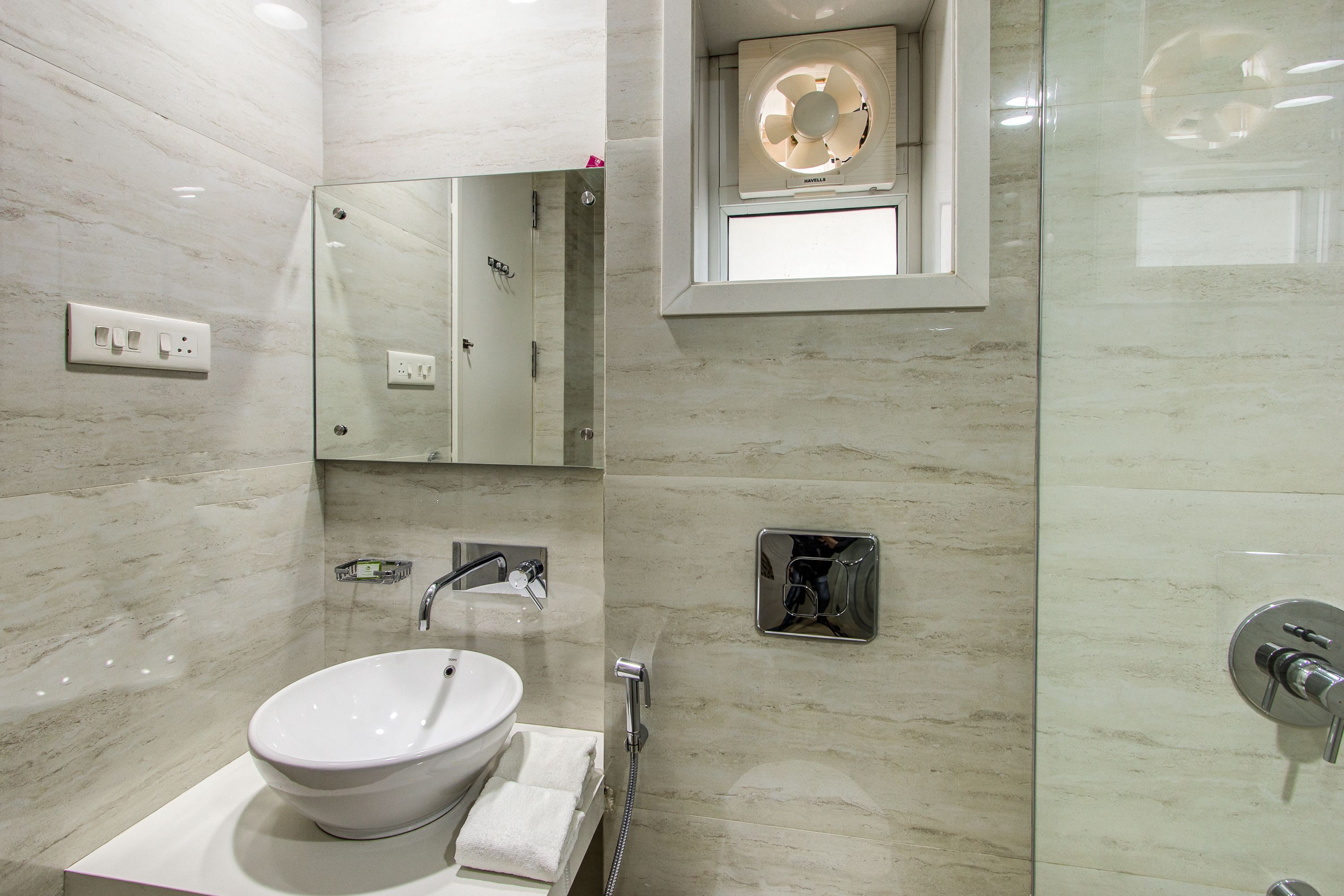 Een moderne badkamer met een wit wastafel, een spiegel en een handdouche.