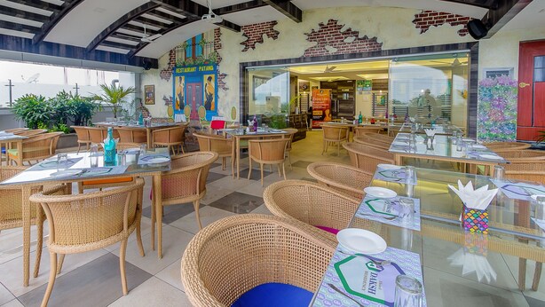Un restaurant doté de mobilier en osier, de tables en verre et offrant une vue sur la mer.