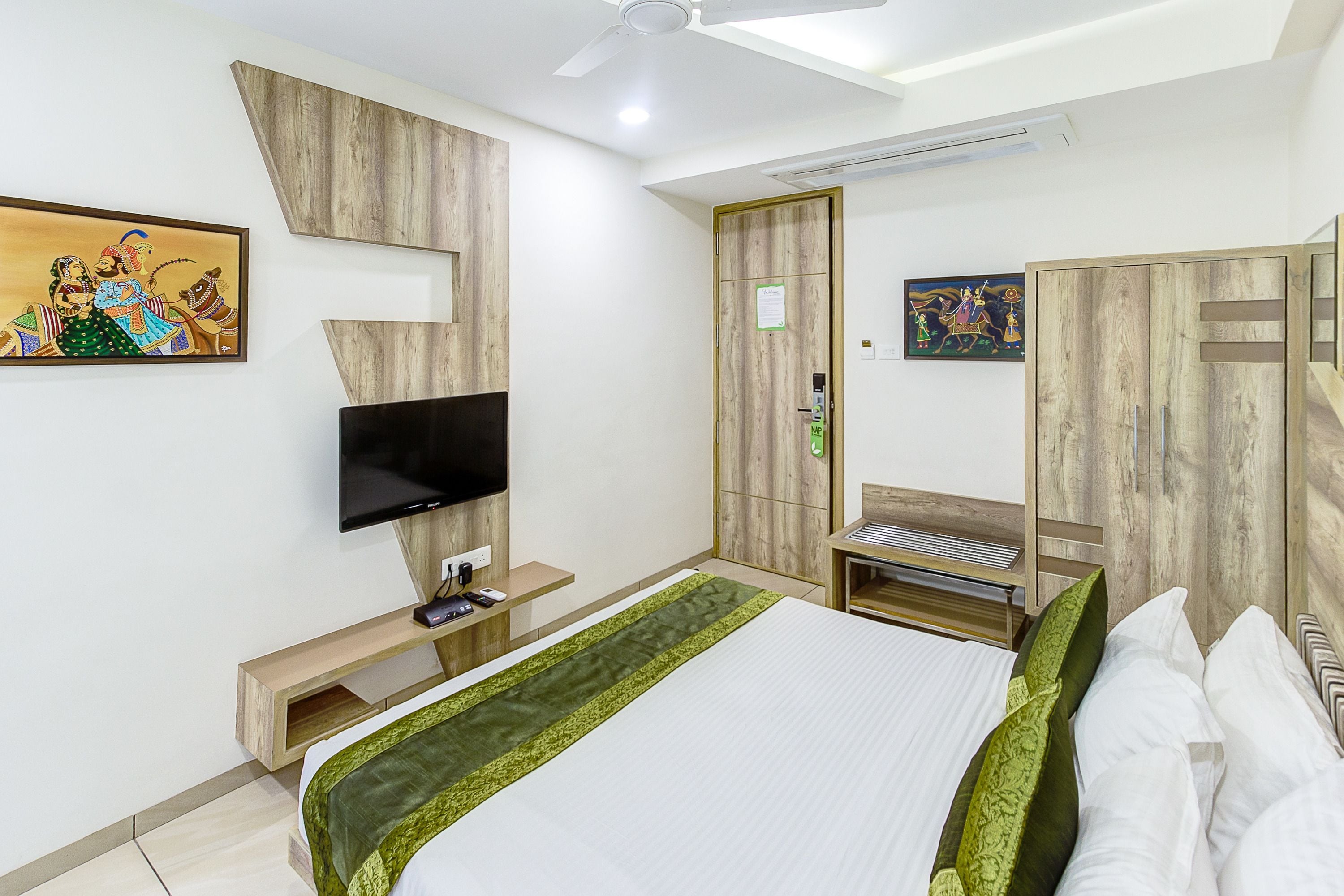 Una habitación de hotel moderna con cama, televisión, armario y un cuadro en la pared.