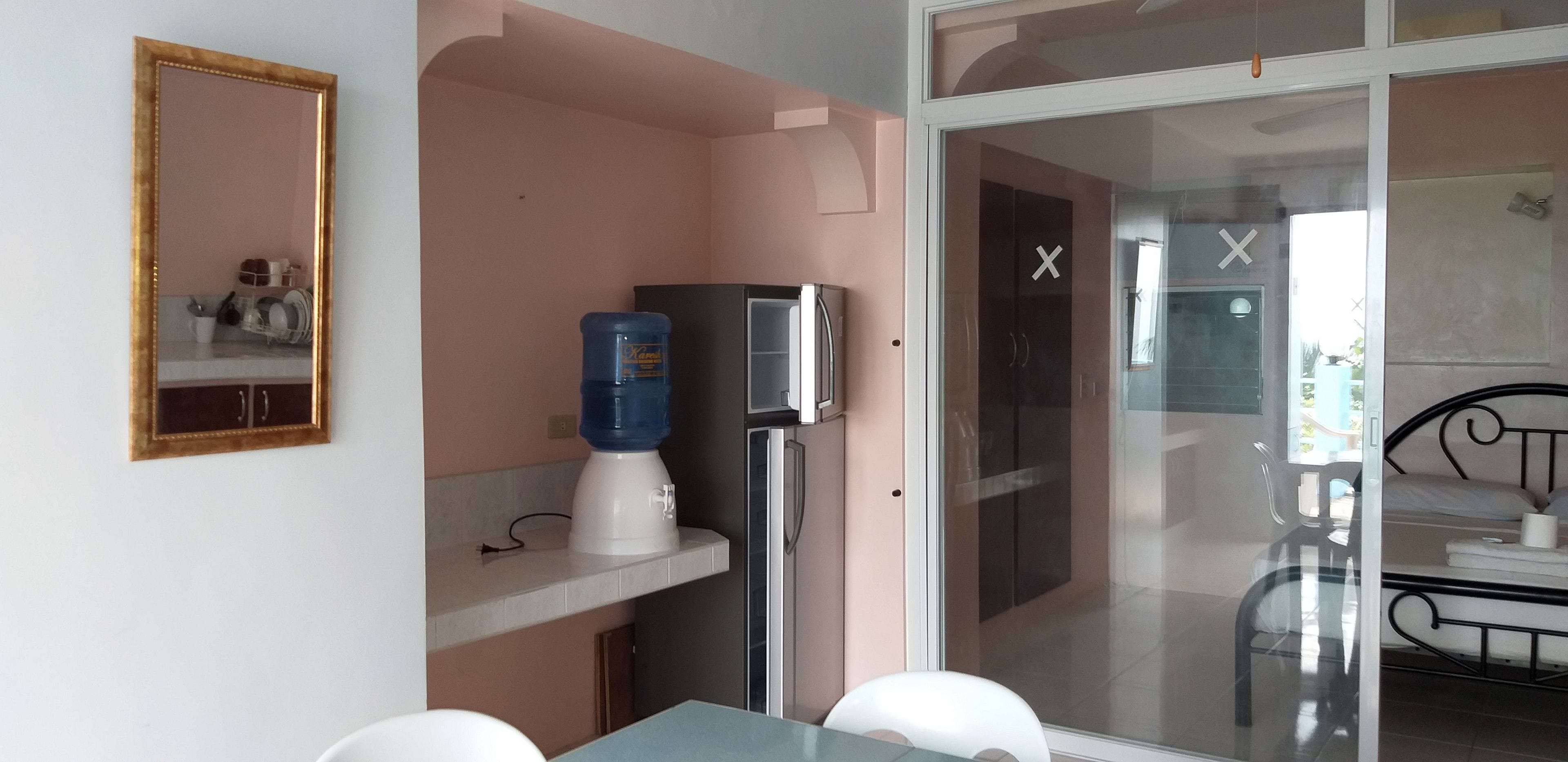 Eine kleine Küche mit Kühlschrank, Wasserspender und Mikrowelle.