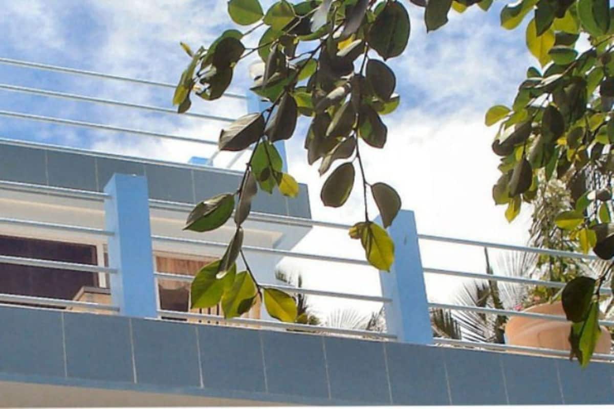 A modern building with a blue facade and a balcony with metal railings.