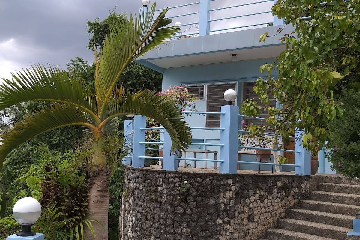 A blue building with a stone staircase leading to a balcony.