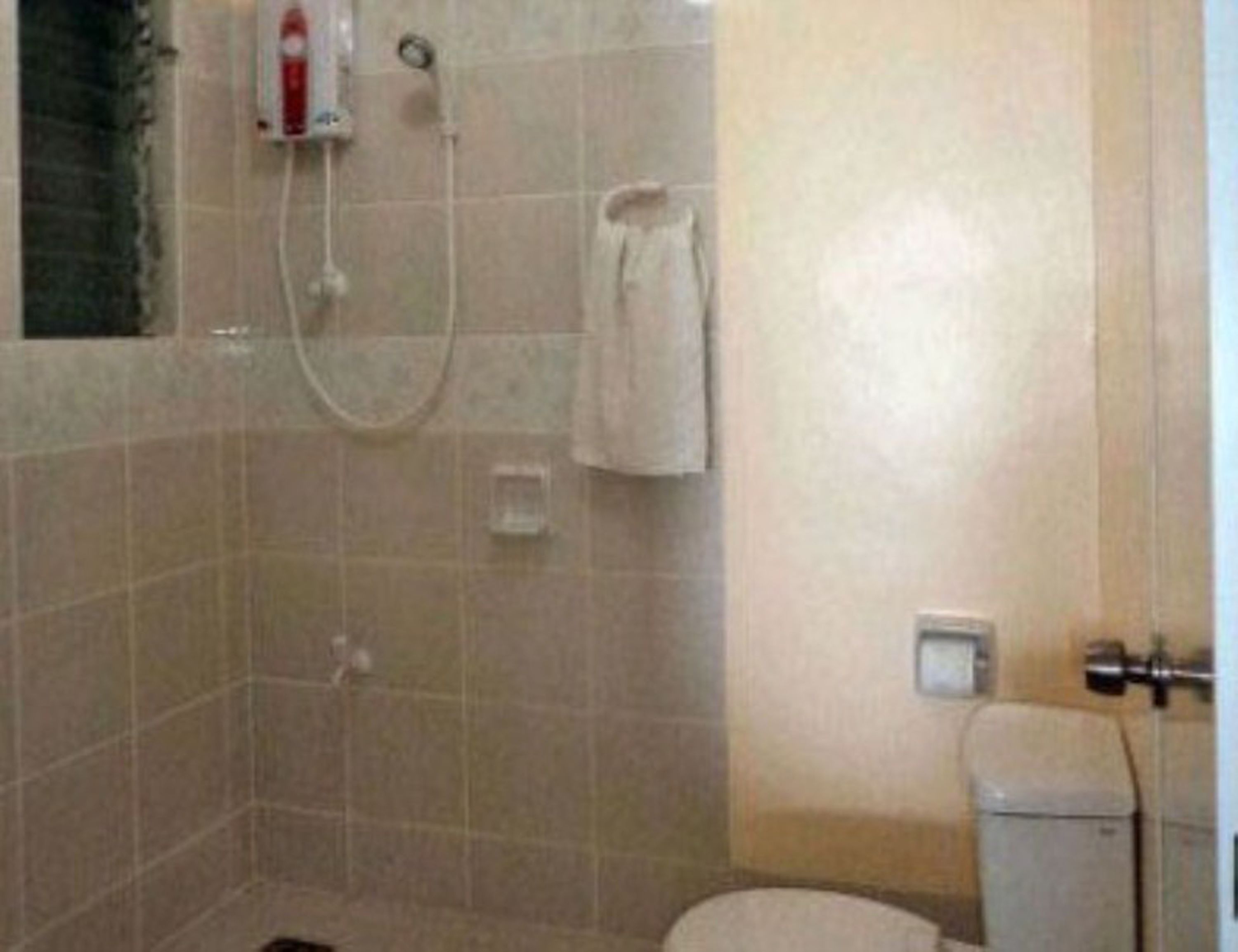 A small bathroom with a toilet, a shower, and a towel hanging on the wall.