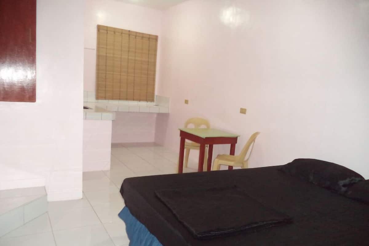 A small, clean room with a bed, a desk, and a chair.