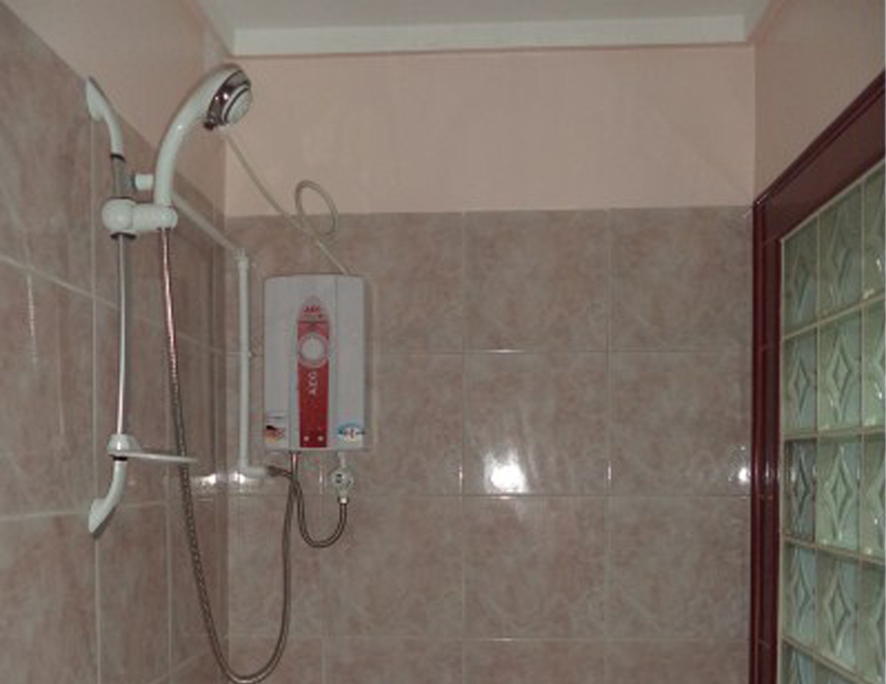 A bathroom with a shower, a handheld showerhead, and a wall-mounted control panel.