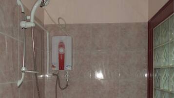 A bathroom with a shower, a handheld showerhead, and a wall-mounted control panel.