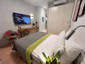 A hotel room with a bed, a desk, a chair, a TV, and a wardrobe. - Dizengoff 208 Hotel (Tel Aviv)